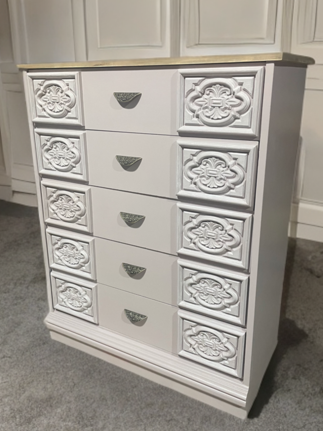 An upcycled or refinished stand up 5 drawer dresser in white with ornate drawer fronts, a natural wood tone top